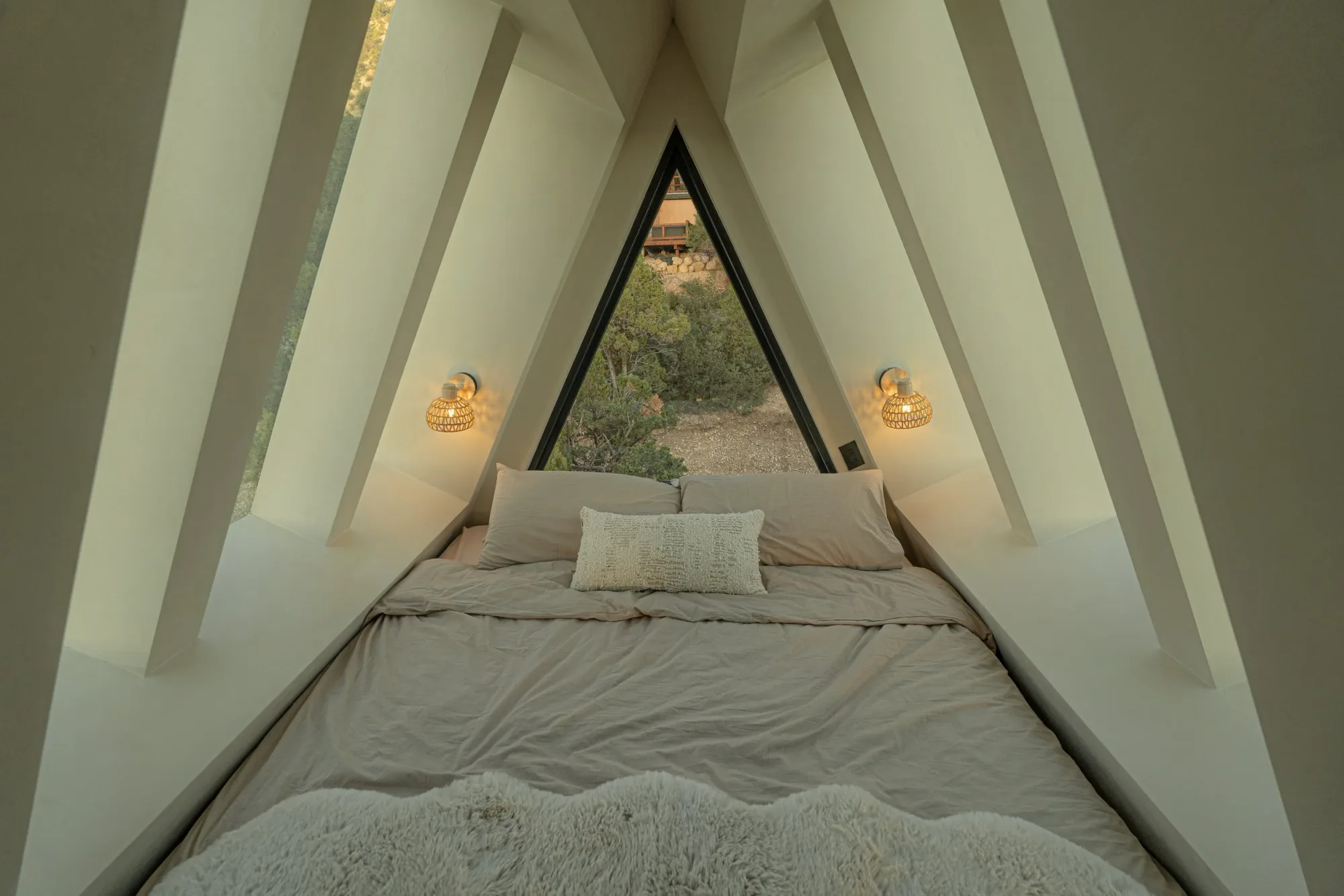 The sky loft: a bed tucked under the peak of the A-frame, with triangular windows to the sky.