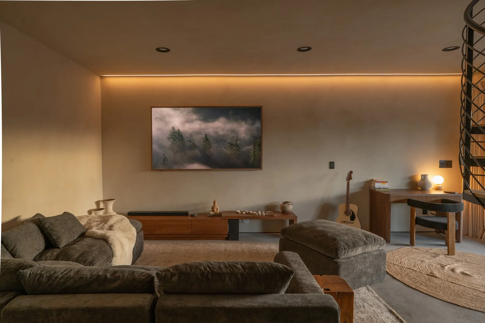 The home theater style living room: a deep sectional facing a wall screen, with warm cove lighting at dusk.